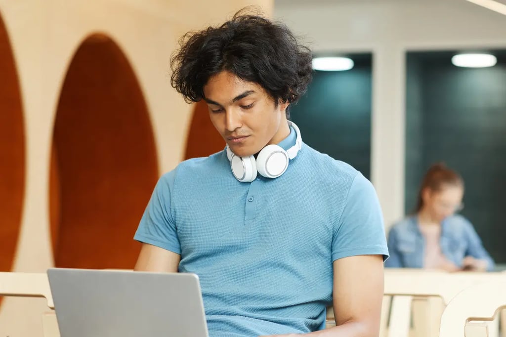 Affordable homeschooling online with a teenage student studying independently on a laptop in a modern public space.