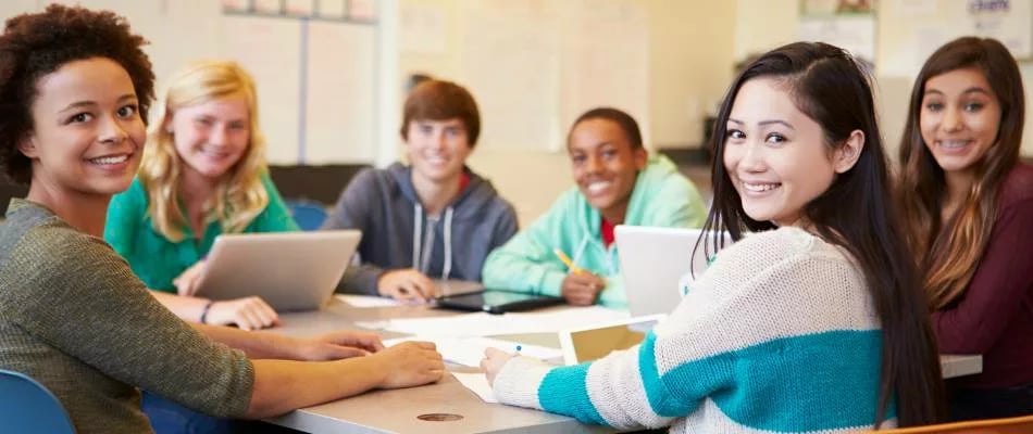 Benefits of online homeschooling for high school students shown by a diverse group collaborating with laptops and books in a study session.