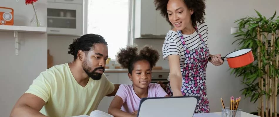 Benefits of project-based learning in homeschool shown by a family collaborating on an educational activity around a laptop.
