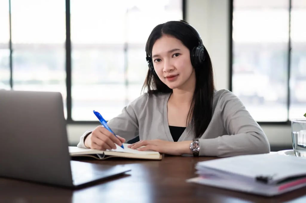 Home school programs for high school student studying with headphones and notebook in front of a laptop