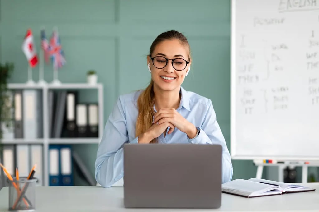Accredited online homeschool programs teacher smiling during a virtual lesson with a laptop and whiteboard in the background