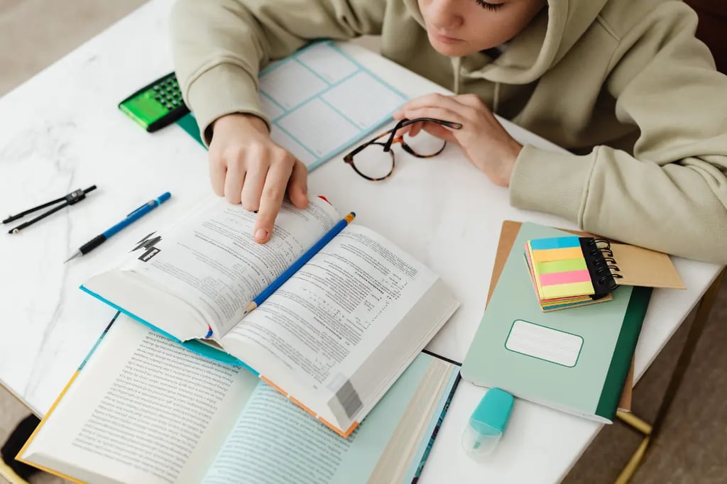 Virtual learning student in a hoodie studying with textbooks, notes, and stationery on a desk
