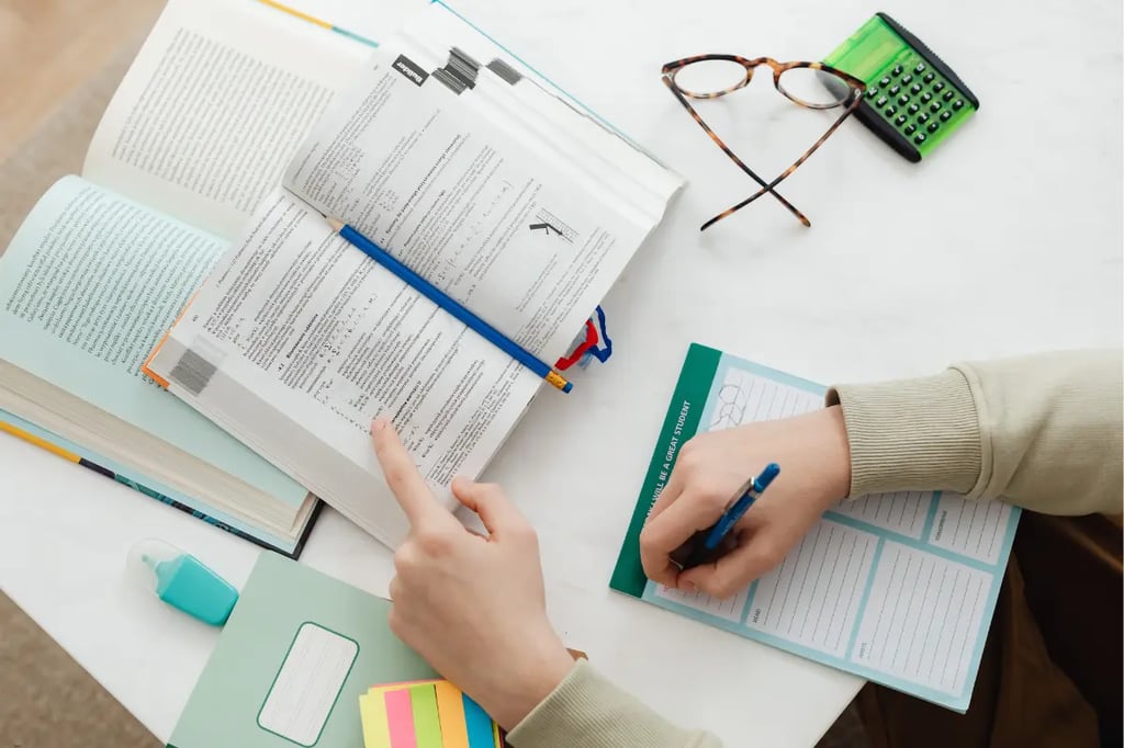 Virtual learning student in a hoodie studying with textbooks, notes, and stationery on a desk