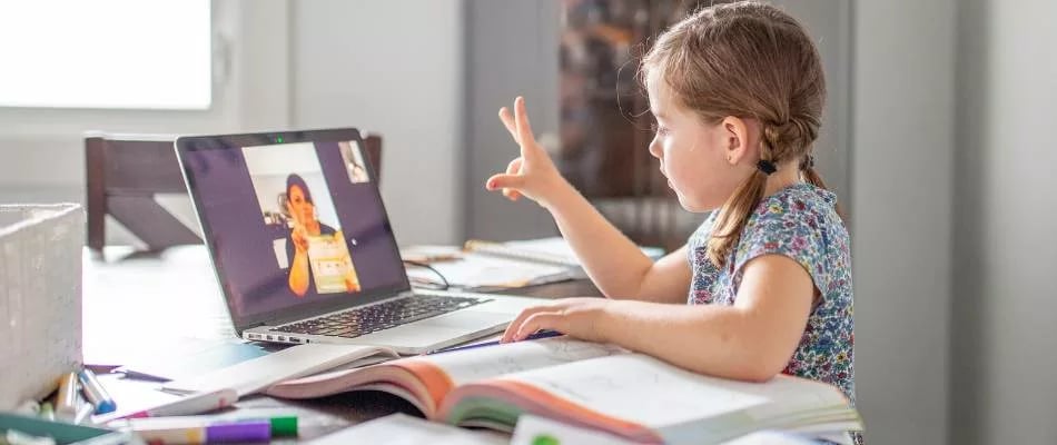 Mastery-based learning shown by a young student using sign language during an interactive video lesson at home.