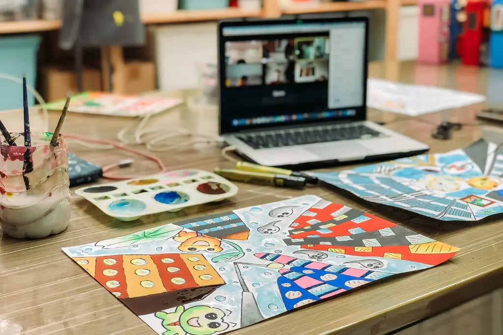 Inquiry-based learning setup with a laptop, colorful paintings, and art supplies on a desk