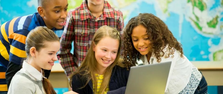 Online homeschooling for middle school students shown by a diverse group of kids gathered around a laptop in a learning environment.