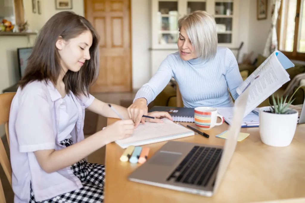 Best online homeschool setup with a mother helping her daughter study at a kitchen table with a laptop and notebooks