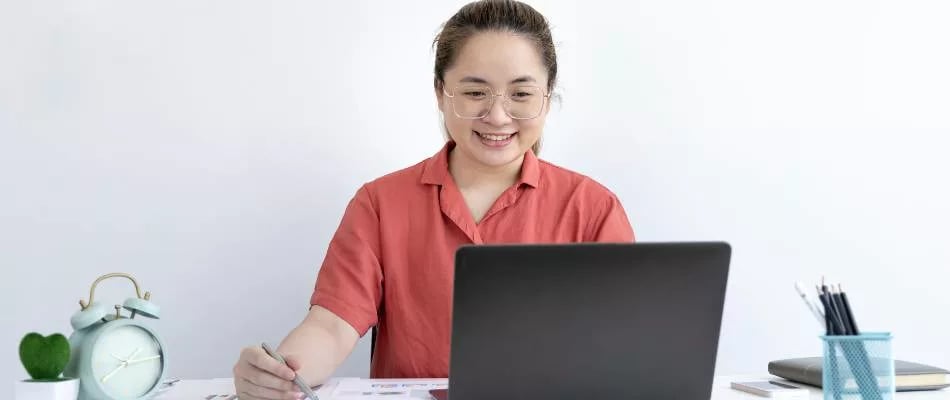 Project-based learning strategies for online homeschoolers illustrated by a student smiling while working independently at a laptop.