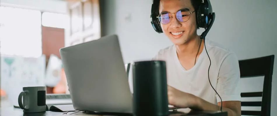 Role of accreditation in online homeschooling shown by a happy student learning with headphones and a laptop at home.