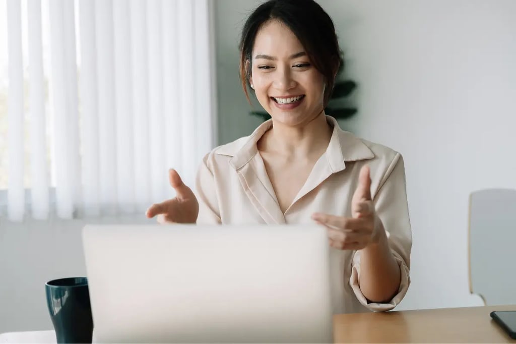 Woman smiling while engaging in a video call on her laptop in a bright home office