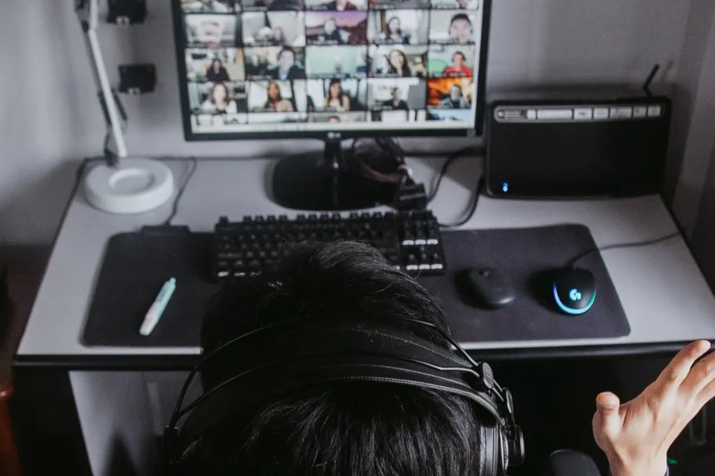 Project based homeschooling with a student participating in a large online video class using a desktop computer and headset.
