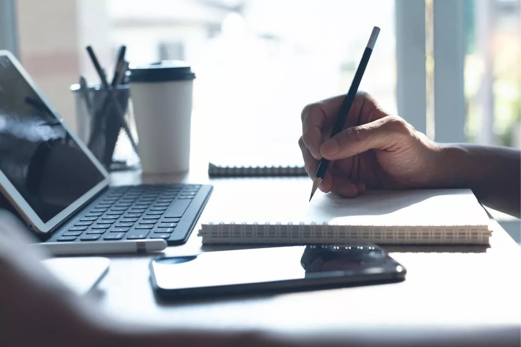 Advantages of student-centered learning shown by a hand writing in a notebook beside a tablet, phone, and coffee cup.