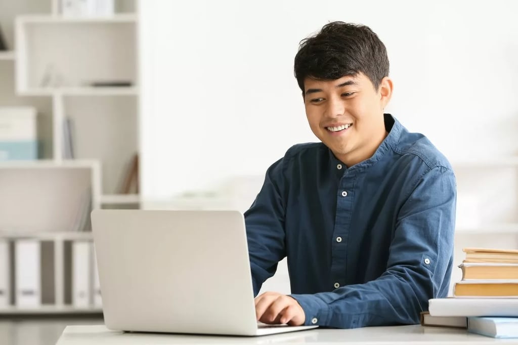 Homeschool curriculum represented by a smiling student using a laptop surrounded by books in a bright, organized study space.
