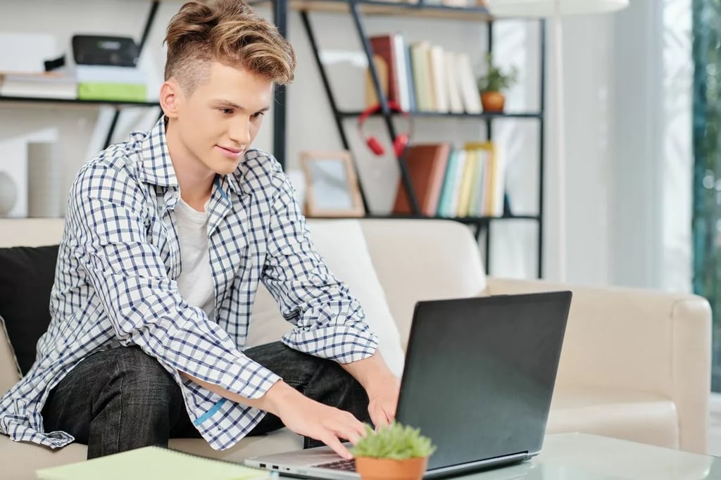 Online middle school programs represented by a smiling teen using a laptop while studying in a comfortable, modern home setting.