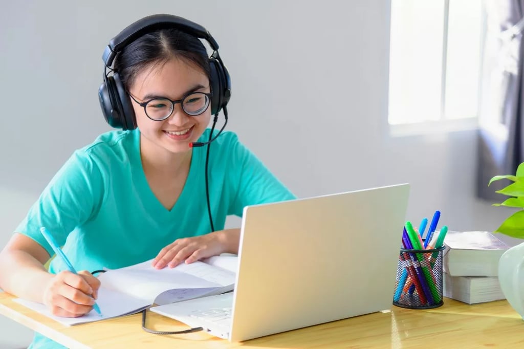Private online high school illustrated by a smiling student wearing headphones and studying with a laptop and notebook at a desk.