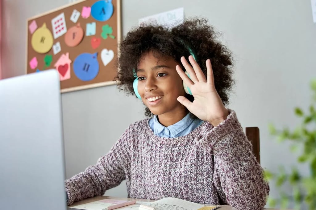 Project based learning shown by a cheerful student engaging in an interactive online class with headphones and a raised hand.