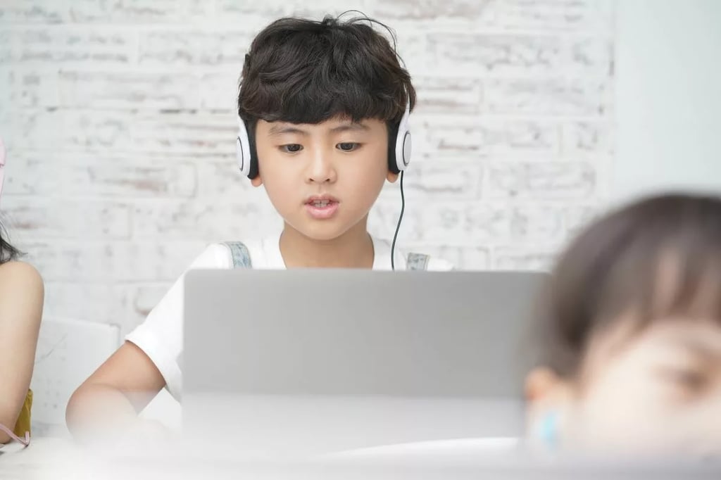 The best homeschool programs illustrated by a focused boy using headphones and laptop in a modern learning environment