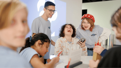 Private online homeschool students engage in a hands-on learning activity, laughing and collaborating in a bright, interactive classroom.