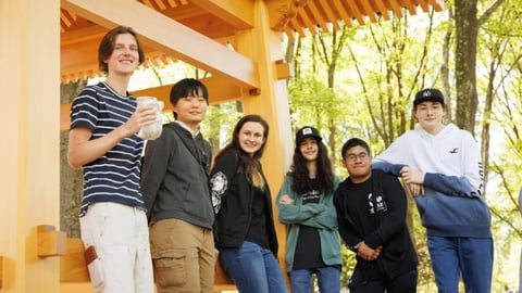 Private online homeschool students gather outdoors under a wooden pavilion, smiling and posing for a group photo.