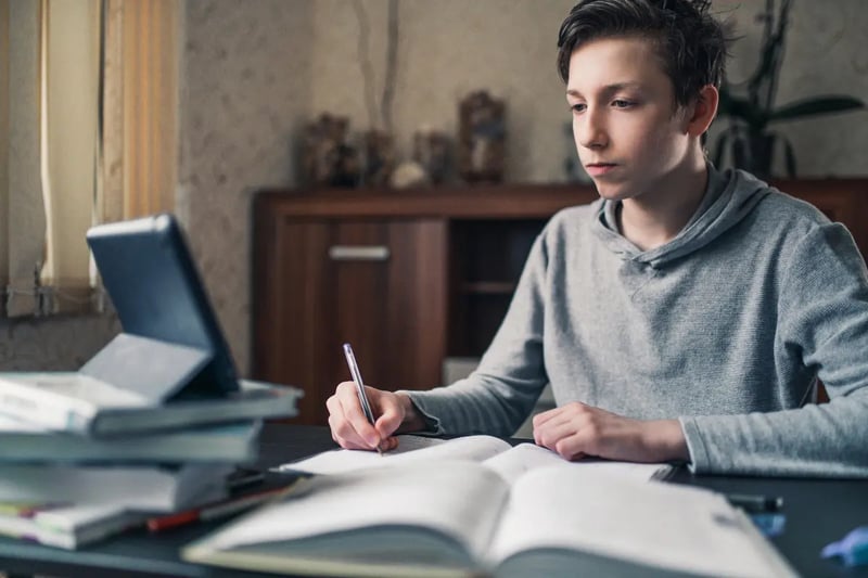 Online homeschool student studying independently at a desk with books and a laptop