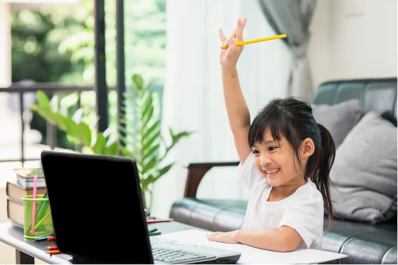 Interest-based learning young student raising hand excitedly during an interactive online class.